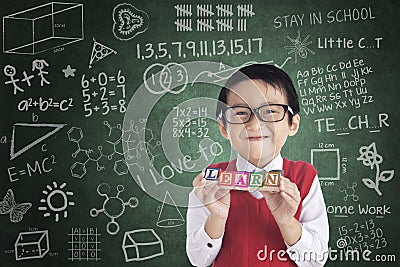 Cheerful boy student holding LEARN block Stock Photo