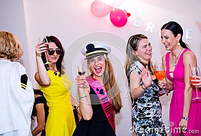 Cheerful bride and bridesmaids celebrating hen party with drinks Stock Photo