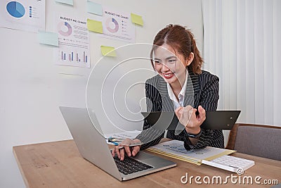 Cheerful business lady working on laptop in office, Asian happy beautiful businesswoman in formal suit work in workplace Stock Photo