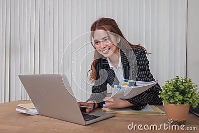 Cheerful business lady working on laptop in office, Asian happy beautiful businesswoman in formal suit work in workplace Stock Photo