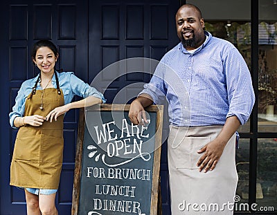 Cheerful business owners standing with open blackboard Stock Photo