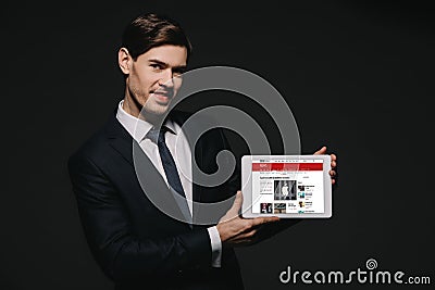 Cheerful businessman holding digital tablet with bbc news app in screen isolated Editorial Stock Photo