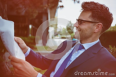 Cheerful businessman reading newspaper in yard Stock Photo