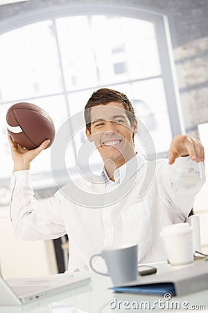 Cheerful businessman throwing football Stock Photo