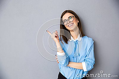 Cheerful businesswoman in glasses pointing away Stock Photo