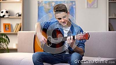 Cheerful Caucasian teenager playing guitar, enjoying favorite hobby, leisure Stock Photo