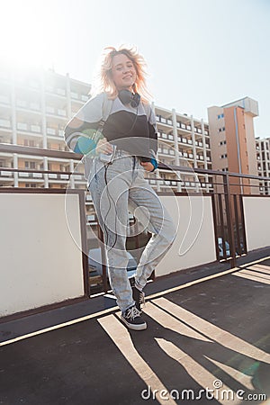 Cheerful caucasian woman in her 20s wearing 90s-inspired clothes and posing to camera with old mini cassette player Stock Photo