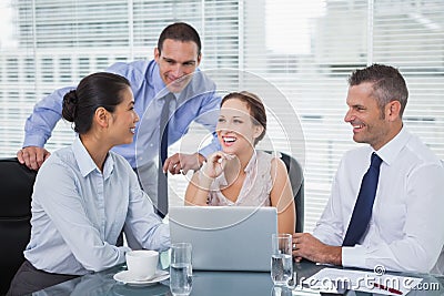 Cheerful colleagues around laptop working together Stock Photo