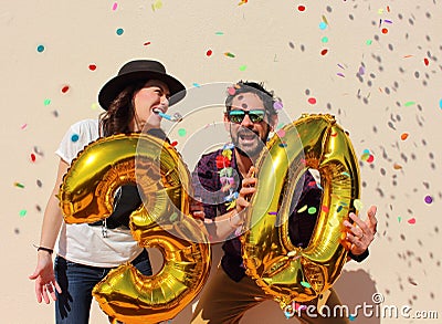 Cheerful couple celebrates a thirty years birthday with big golden balloons Stock Photo