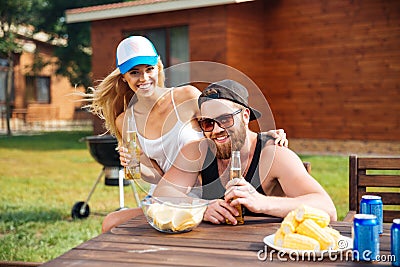 Cheerful couple eating and drinking beer outdoors at the table Stock Photo