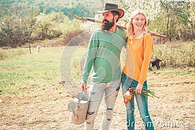 Cheerful couple of farmers standing in vegetable garden. Young Couple gardening in the garden. Portrait of pair of farms Stock Photo