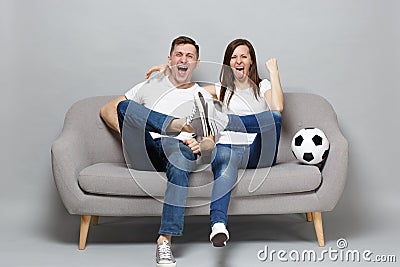 Cheerful couple woman man football fans cheer up support favorite team with soccer ball clenching fist, showing tongue Stock Photo