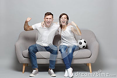 Cheerful couple woman man football fans cheer up support favorite team with soccer ball, hugging, clenching fists Stock Photo