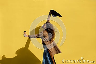 Girl with a cup of coffee on a sunny day near the yellow wall Stock Photo