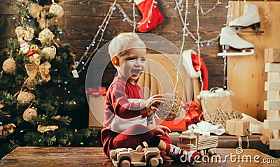 Cheerful cute child opening a Christmas present. kiddy. Kid having fun near Christmas tree indoors. New year kids Stock Photo