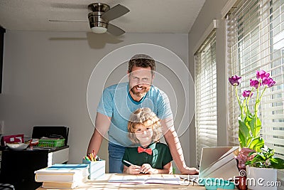 cheerful daddy writing school homework with his kid son in classroom, fatherhood Stock Photo