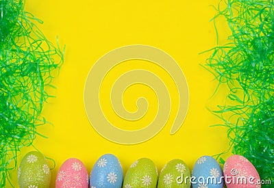 A cheerful Easter background border with sparky, decorative pink, blue and green eggs and plastic Easter grass with a bright Stock Photo