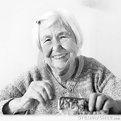 Cheerful elderly 96 years old woman sitting at table at home happy with her pension savings in her wallet after paying Stock Photo