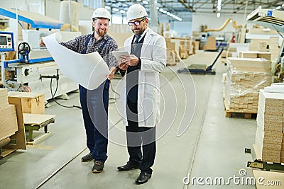 Cheerful engineer presenting blueprint to investor in white coat Stock Photo