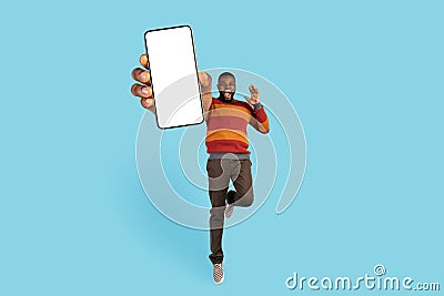 Cheerful Excited Black Male Jumping With Big Blank Mobile Phone In Hand Stock Photo