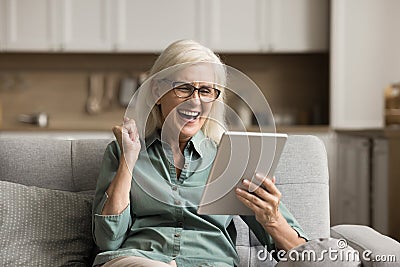 Cheerful excited elderly woman using digital tablet computer Stock Photo