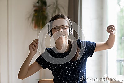 Cheerful excited millennial girl wearing glasses, wireless headphones Stock Photo