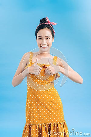 Cheerful excited pinup girl showing thumbs up over blue background Stock Photo