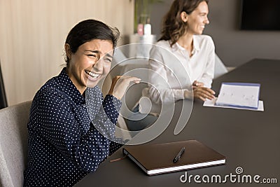 Cheerful excited pretty Indian employee laughing at corporate meeting Stock Photo