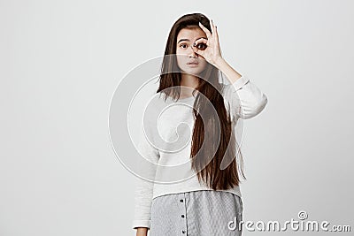 Cheerful excited teenage girl with dark long straight hair showing Ok gesture with hand, enjoying her carefree happy Stock Photo