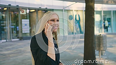 Cheerful executive girl waving with hand. Adult blond businesswoman in suit sitting on bench and waving with hand Stock Photo