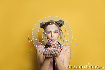 Cheerful fashion model woman and colorful falling confetti on yellow background Stock Photo