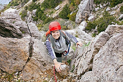 Cheerful female climber ascending a rock Stock Photo