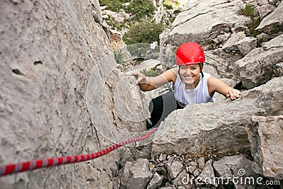 Cheerful female climber ascending a rock Stock Photo