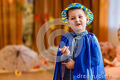 Cheerful five-year-old child in a blue suit and hat dancing on a blurred background of kindergarten Stock Photo