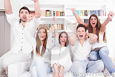 Cheerful friends watching football game on tv Stock Photo