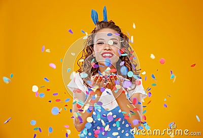 Cheerful funny young woman with festive confetti on yellow Stock Photo