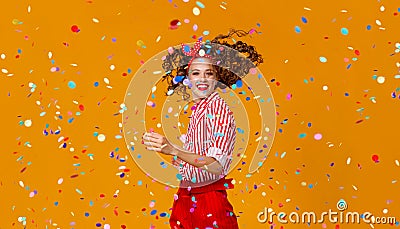 Cheerful funny young woman with festive confetti on yellow Stock Photo