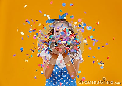 Cheerful funny young woman with festive confetti on yellow Stock Photo