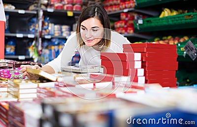 cheerful girl customer looking for tasty sweets in supermarket Stock Photo