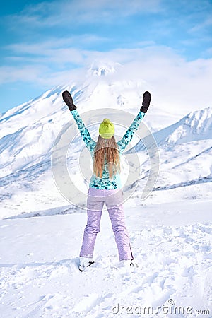 Cheerful girl snowboarder in blue sweater in front of snowy mountains Stock Photo