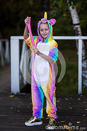 Cheerful girl in a unicorn costume plays with a pink slime Stock Photo