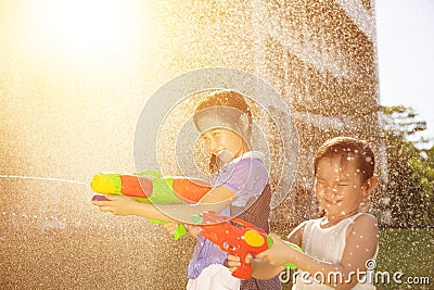 Cheerful girls playing water guns in the park Stock Photo