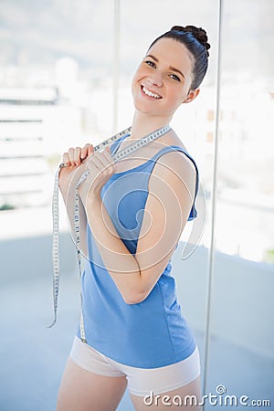 Cheerful gorgeous woman in sportswear holding measuring tape Stock Photo