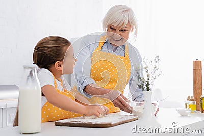 Cheerful granny holding flour and looking Stock Photo