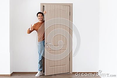 Cheerful guy looking out of door showing thumb up gesture Stock Photo