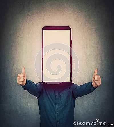 Cheerful guy with smartphone instead his head, shows thumbs up gesture. Telecommunications marketing, approval symbol. Obsessed Stock Photo