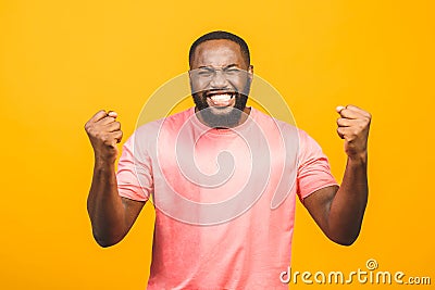 Cheerful handsome African guy making yes gesture while excited about winning. Ecstatic young fan rooting and expressing support. Stock Photo