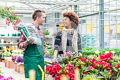 Cheerful handsome worker in a flower shop talking with a beautiful customer Stock Photo