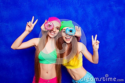 Cheerful happy hipster sisters having fun and holding donutes Stock Photo