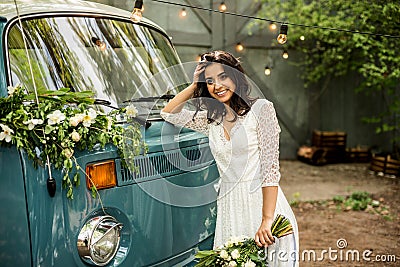 Cheerful happy young bride hold bouquet near retro-minibus. Close-up. Stock Photo